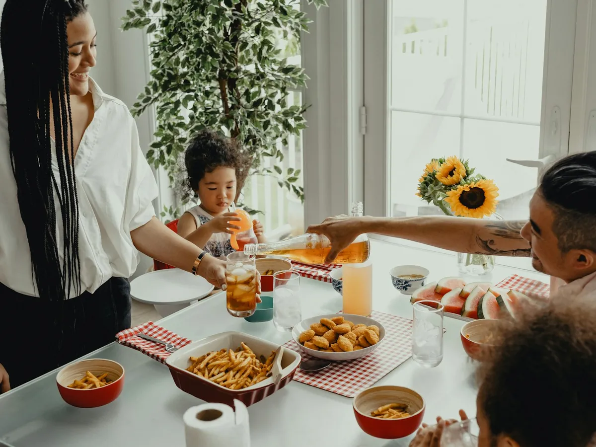 A mother serving a homemade dish to her children at a sunny family table with sunflowers