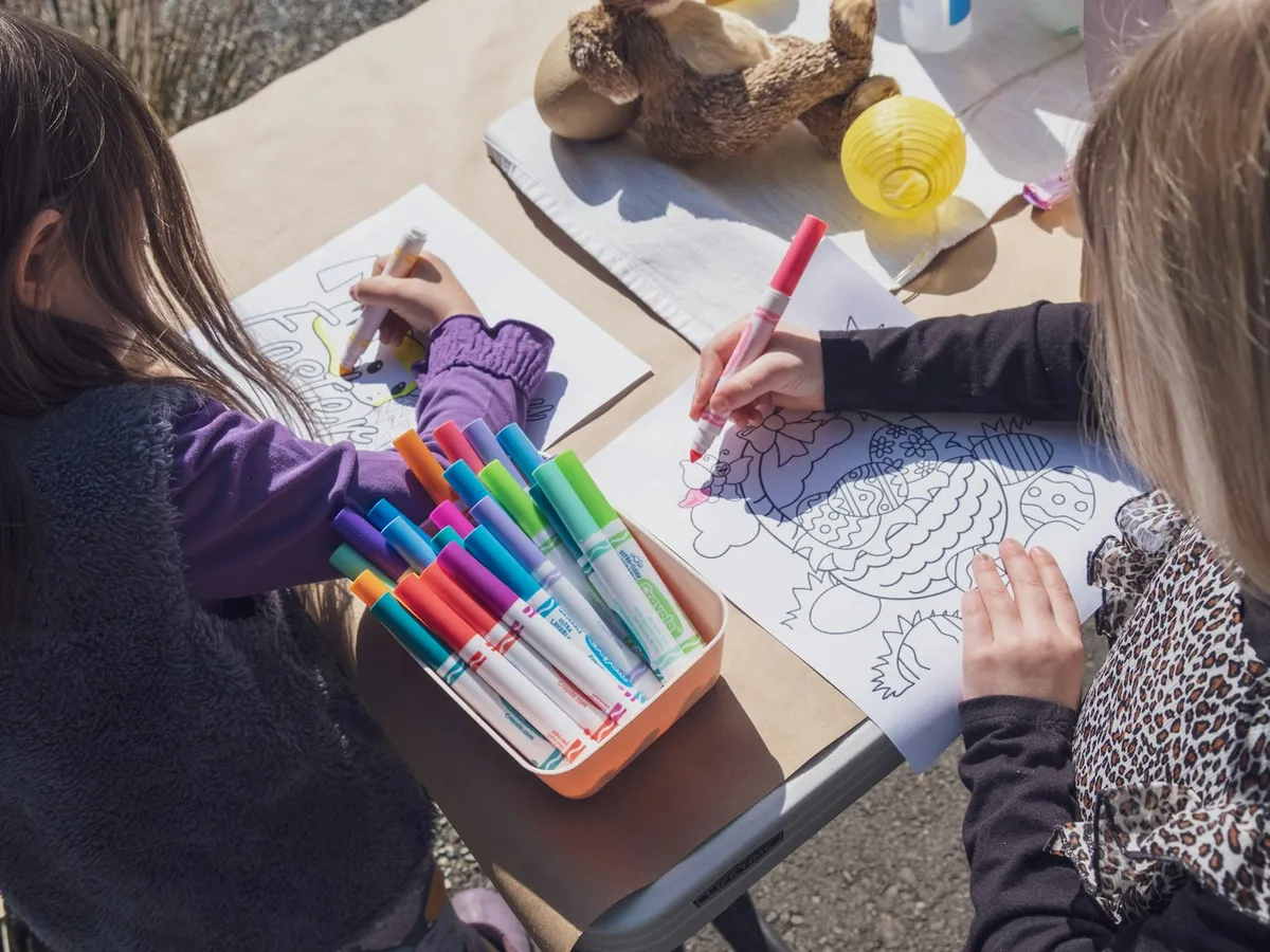 Two children coloring detailed pattern pages together with markers at a table