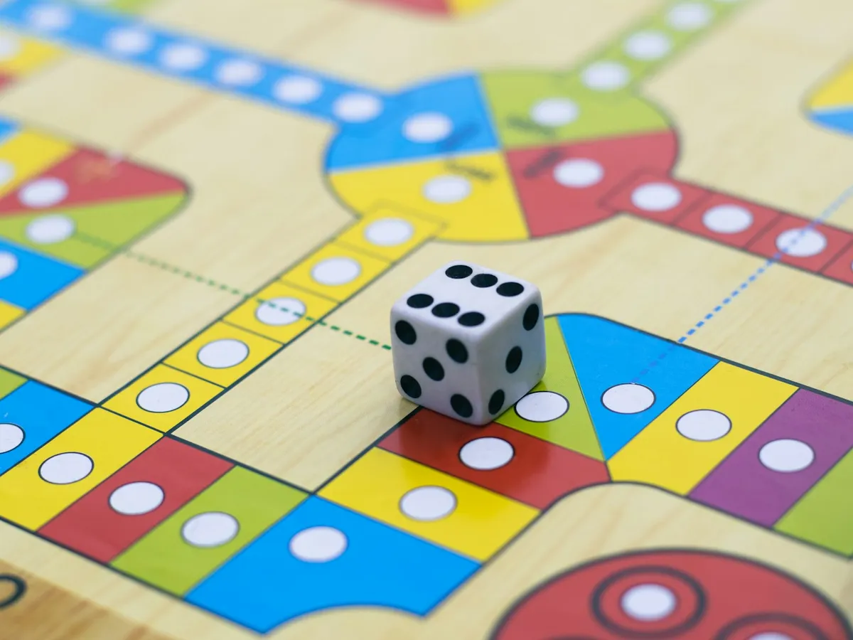A white die resting on a colorful wooden board game